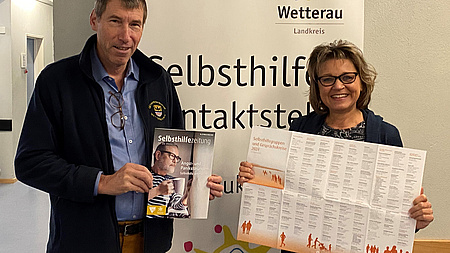 Prof. Dr. Reinhold Merbs und Anette Obleser präsentieren die aktuell erschienene 47. Selbsthilfezeitung und das Faltblatt der für 2024 aktiv gemeldeten Selbsthilfeangebote.